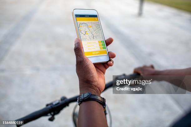 senior afrikaanse delivery man controleren mobiele app voor de richting in de stad - route stockfoto's en -beelden