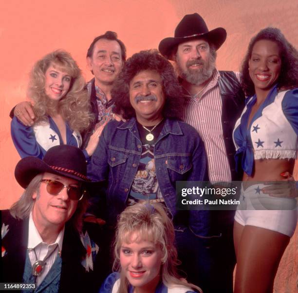 Portrait of the members of American Tejano group Texas Tornados as they pose backstage, with three members of the Dallas Cowboys Cheerleaders, at the...