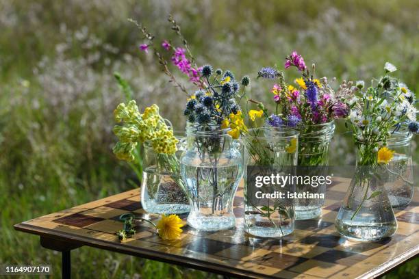 fresh wild flowers in upcycling jars on upcycling chess board table - fiore di campo foto e immagini stock