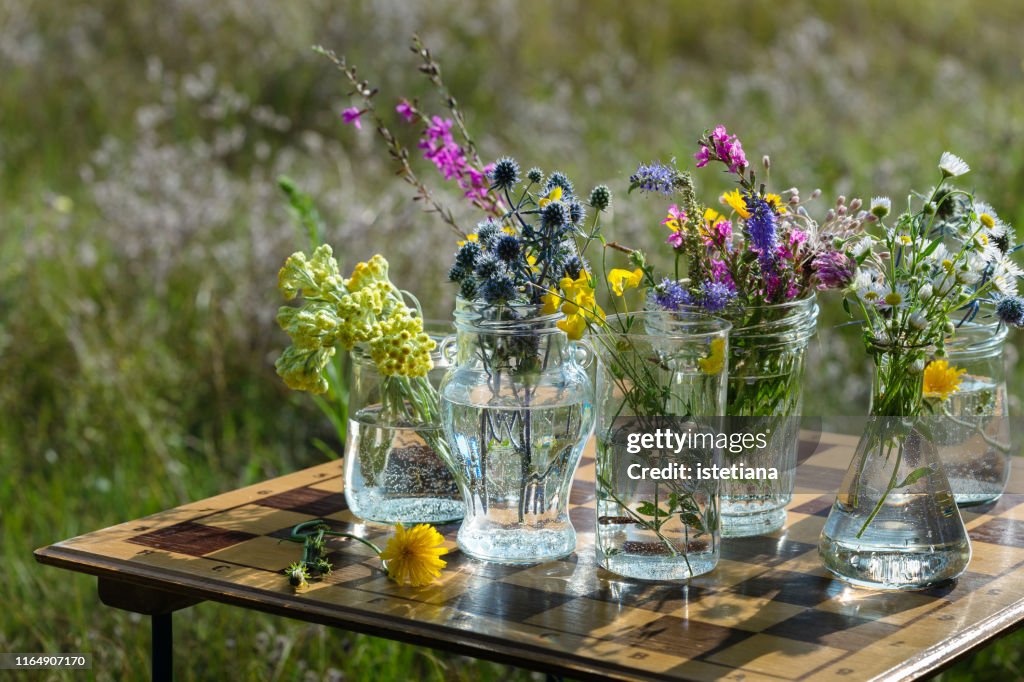 Fresh wild flowers in upcycling jars on  upcycling chess board  table