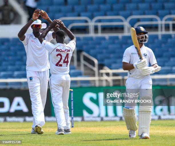 Jason Holder and Kemar Roach of West Indies celebrate the dismissal of Ajinkya Rahane of India during day 1 of the 2nd Test between West Indies and...