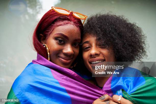 two women wrapped in pride flag - london pride stock-fotos und bilder