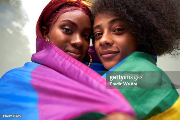 two women wrapped in pride flag - lésbica imagens e fotografias de stock