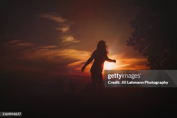 middle aged woman dances in a silhouette cloudscape scene in the summer - woman face silhouette stock pictures, royalty-free photos & images