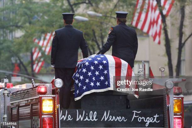 Firefighters stand atop a fire engine with the flag draped casket of fellow fireman Lt. Dennis Mojica September 21, 2001 during a funeral service at...