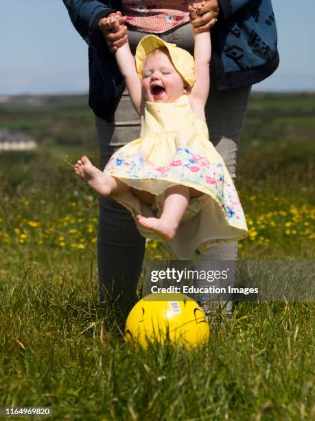 Baby girl and mum kicking a ball.