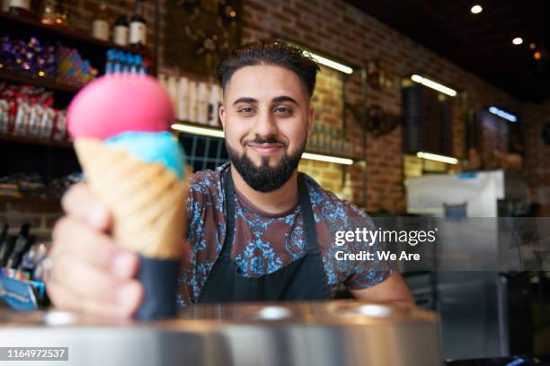 man offering customer an ice cream - ice cream parlour stock pictures, royalty-free photos & images