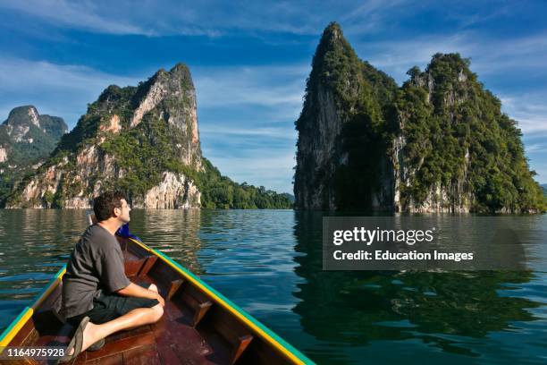 Bodhi Garrett admires the KARST FORMATIONS rising out of CHEOW LAN LAKE in KHAO SOK NATIONAL PARK, THAILAND.