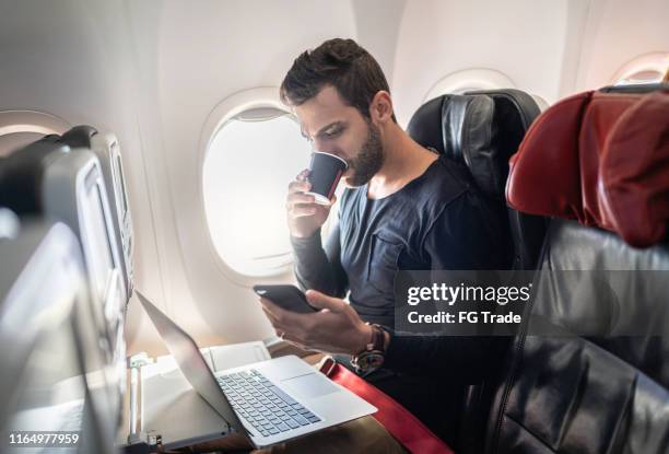 mann arbeitet im flugzeug mit handy und kaffee trinken - businessman working on a laptop with a coffee stock-fotos und bilder