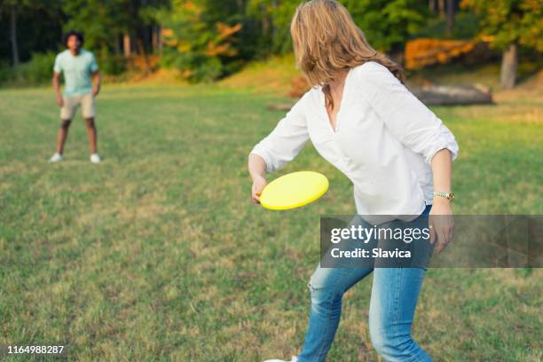 pareja joven lanzando disco en la naturaleza - frisbee fotografías e imágenes de stock