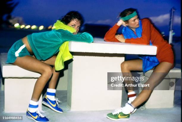 Vogue, April 01, 1977 - Models relaxing after a run at a stone table. On the left, the model wears a green velour sweatshirt and gym shorts from...