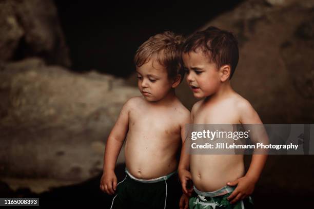 3 year old male fraternal twin toddlers splash in a creek in the summer - 2 year old child fotografías e imágenes de stock