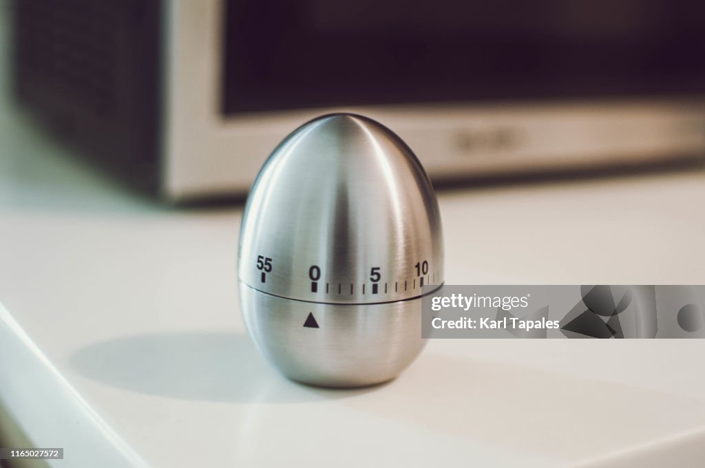 A metal egg kitchen timer on the kitchen table