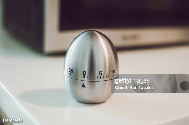 a metal egg kitchen timer on the kitchen table - timer stock pictures, royalty-free photos & images