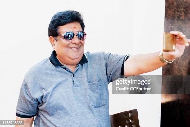 senior adult wearing sunglasses taking selfie at home - old houses in mumbai stock pictures, royalty-free photos & images