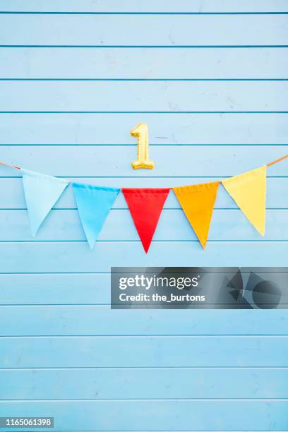 colorful bunting flags/ pennant chain for party decoration and gold colored number one at blue painted wooden wall - about you awards in hamburg stock pictures, royalty-free photos & images
