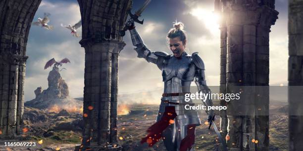 vrouwelijke ridder schreeuwen na de strijd houden zwaarden in de buurt van stenen pilaren - draak fictieve figuren stockfoto's en -beelden