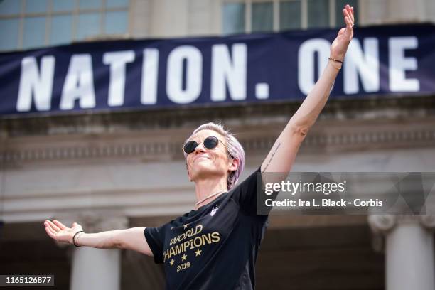 Megan Rapinoe of United States holds out her hands to the crowd with the banner One Nation. One Team behind her during the ceremony on the steps of...