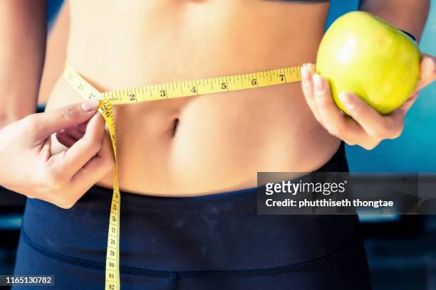 close up slim young woman measuring her waist with a tape measure.healthy lifestyle, diet nutrition concept. - beautiful fat women stockfoto's en -beelden