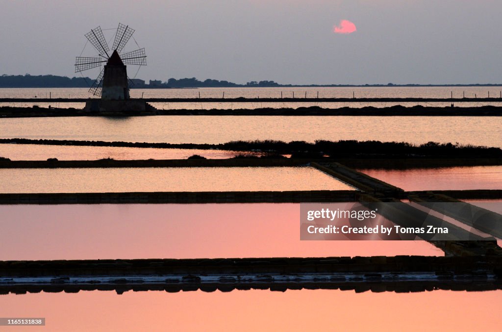 Serene tranquil view of the salt evaporation ponds in Marsala with iconic windmills captured during sunset