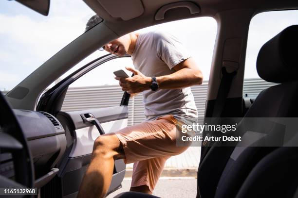 guy getting inside of car sharing using mobile phone app. - car sharing stock pictures, royalty-free photos & images