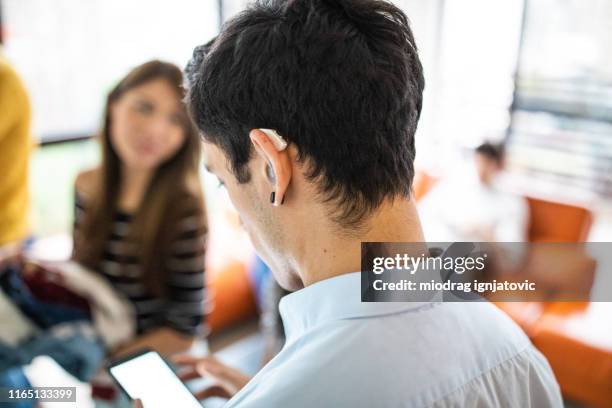 hearing impaired man with assistive technology - hearing aids stock pictures, royalty-free photos & images