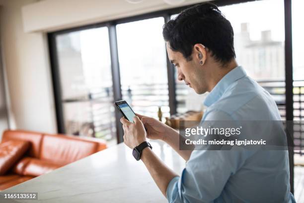 hearing impaired man using smart phone in the kitchen - hearing aid stock pictures, royalty-free photos & images