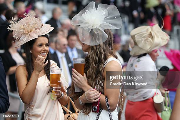 Two women hold pints of lager on ladies day on June 16, 2011 in Ascot, England. The five-day meeting is one of the highlights of the horse racing...