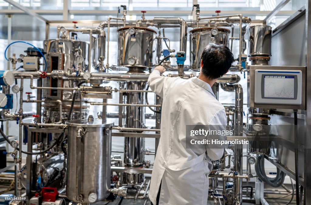 Vista posteriore dello studente maschio che lavora al laboratorio di processo distillando liquidi