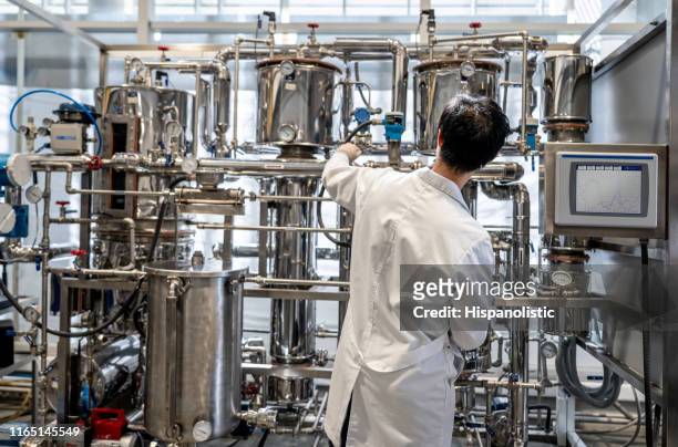 achteraanzicht van mannelijke student werkzaam bij het proceslab distilleren vloeistoffen - scheikundige stockfoto's en -beelden