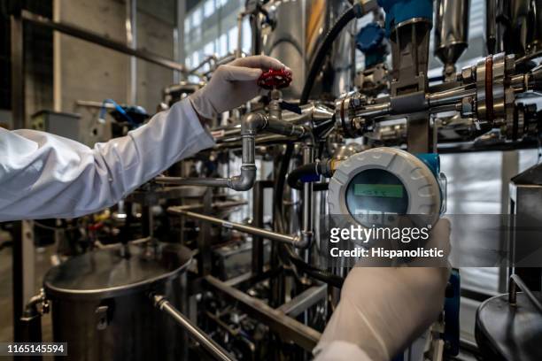 unrecognizable person working at a process lab opening a valve while looking at screen - machine valve stock pictures, royalty-free photos & images