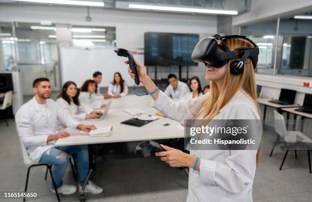 students at college doing an experiment watching a student while using virtual reality headset and joysticks - science demonstration stock pictures, royalty-free photos & images