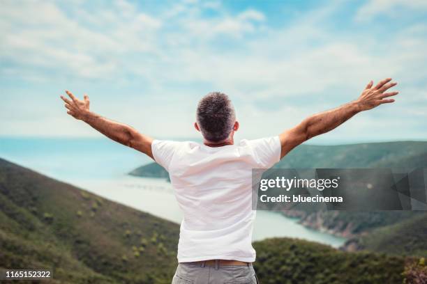 mann auf berggipfel mit ausgestreckte arme - man outstretched arms stock-fotos und bilder