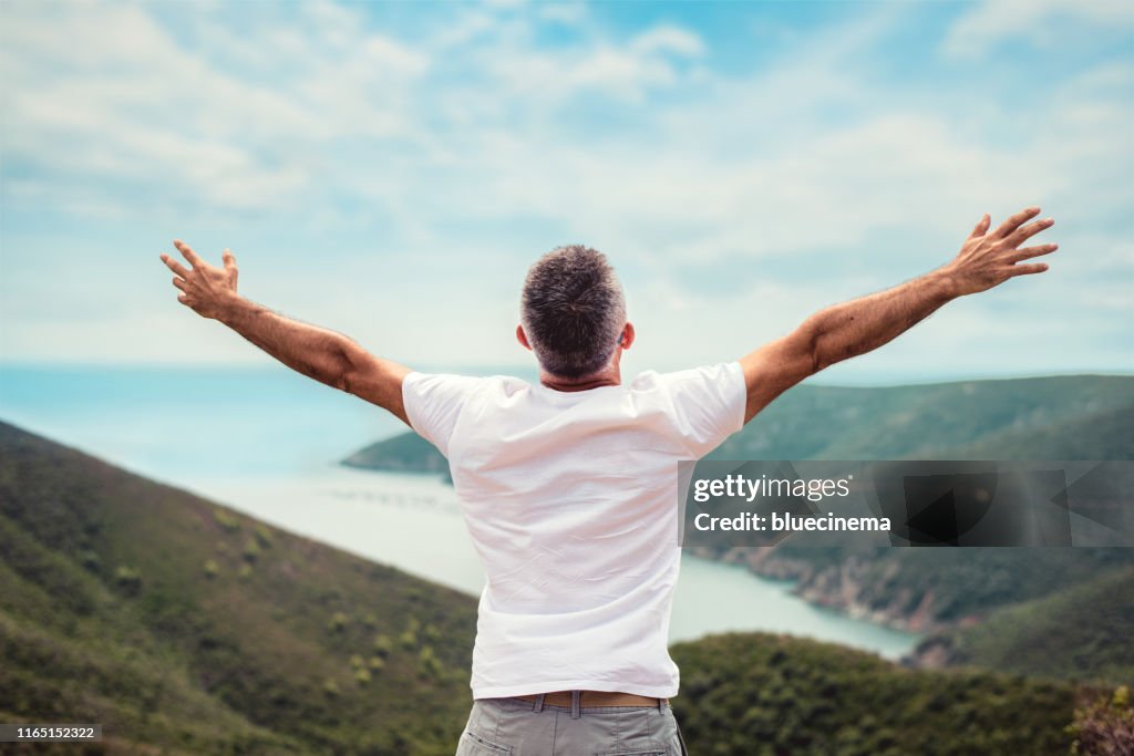 Man with arms outstretched on mountaintop