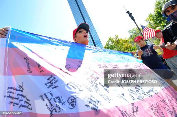 Christen Greczowski, a transgender person, holds up a flag signed by transgender people who have left the Democratic Party, during the "Straight...