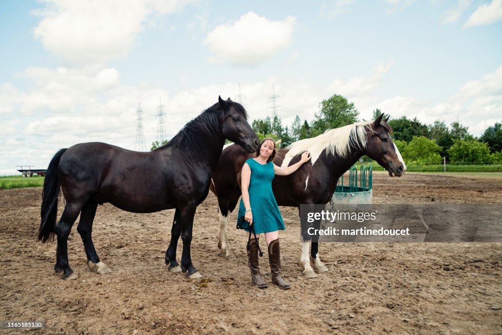 Porträt einer Frau mit Pferden in einem Tierheim.
