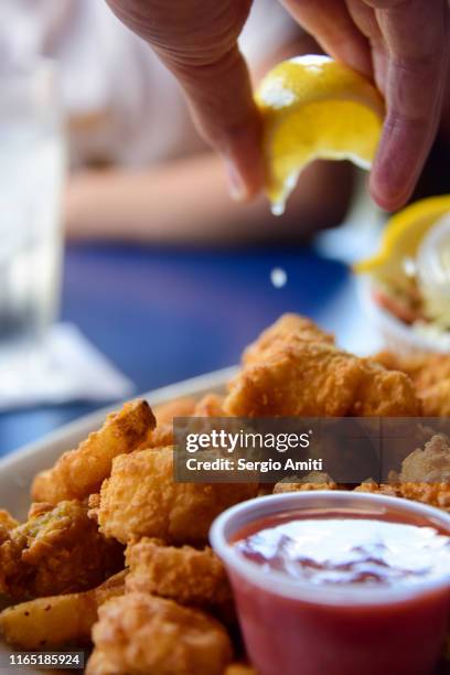 squeezing lemon juice over fried seafood platter - seafood platter foto e immagini stock