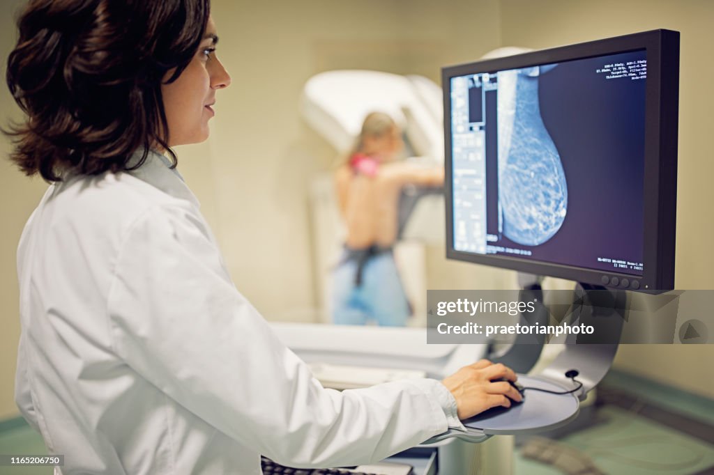 El médico está trabajando con el escáner de rayos X de mamografía en el hospital