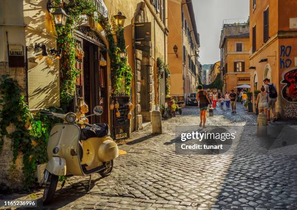 menschen und gebäude in einer gasse von trastevere, rom, italien - vespa stock-fotos und bilder