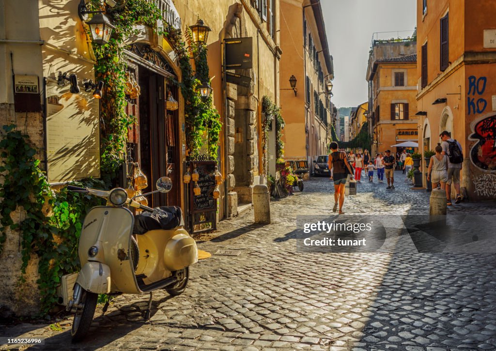 Personas y edificios en un callejón de Trastevere, Roma, Italia