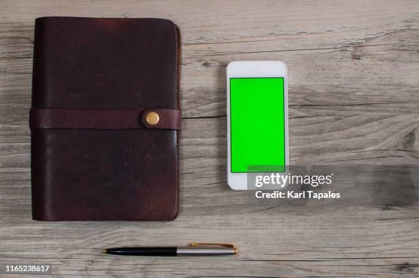 personal organizer and mobile device with green screen on a wooden table - leather journal stock pictures, royalty-free photos & images