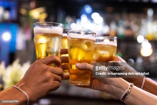 group of happy friends drinking and toasting beer at brewery bar restaurant - friendship concept with young people having fun together at cool vintage pub - focus on middle pint glass - high iso image - brindis fotografías e imágenes de stock
