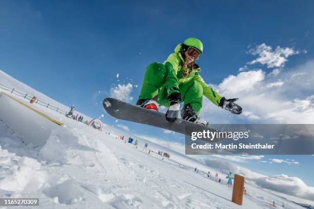 junges mädchen mit snowboard springt über rampe - snowboarding stockfoto's en -beelden