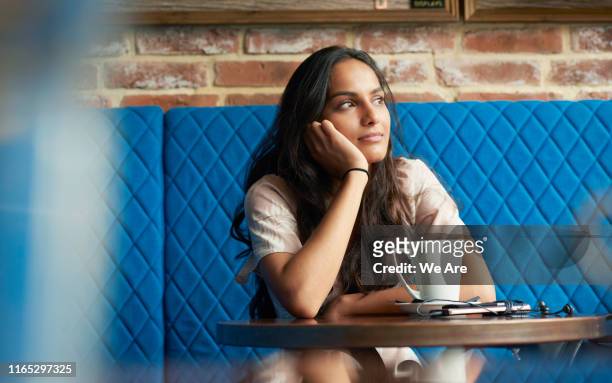 woman sitting in contemplation at a cafe table - day dreaming stock pictures, royalty-free photos & images