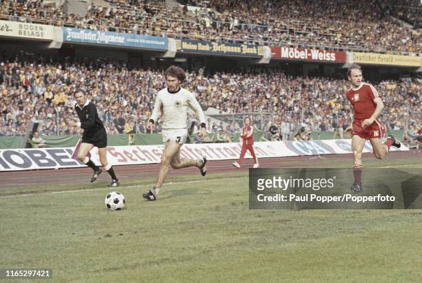 German footballer Paul Breitner pictured making a run with the ball as Polish player Grzegorz Lato runs to intecept during play in the 1974 FIFA...