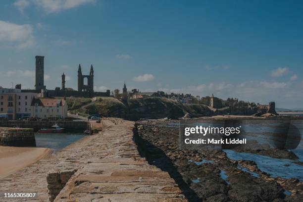 st andrews pier with cathedral and castle visible in the background - st andrews scotland stock pictures, royalty-free photos & images