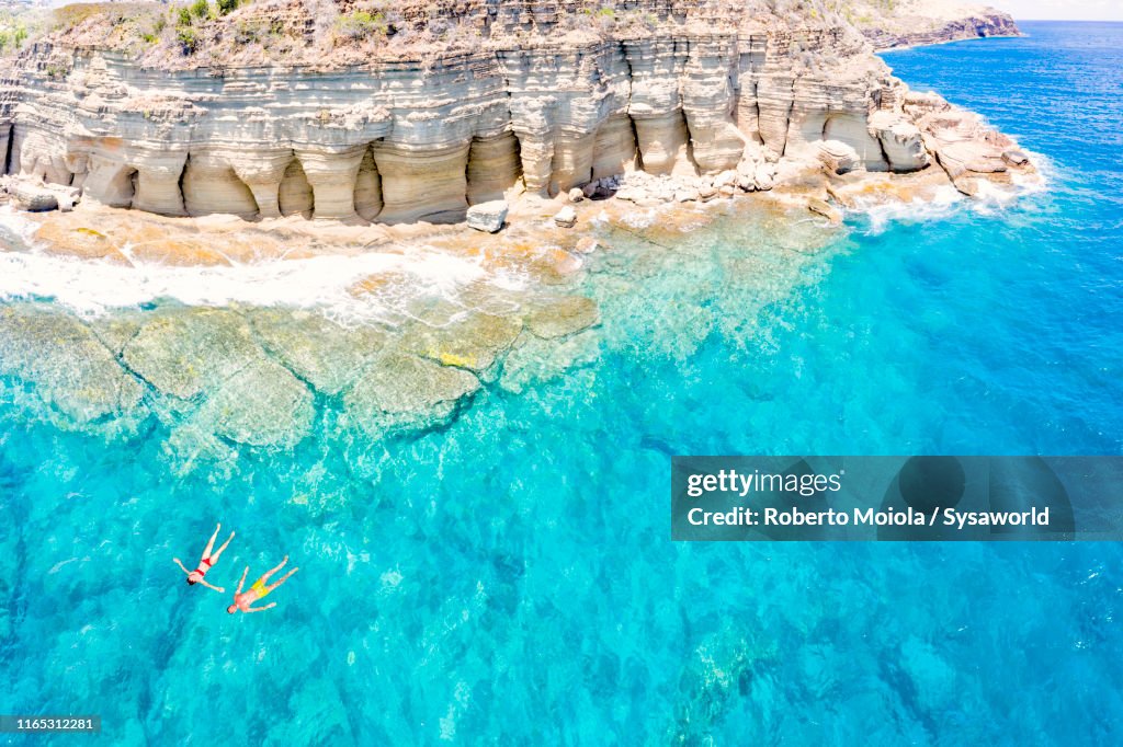 Couple floating in sea, Pillar of Hercules, Antigua
