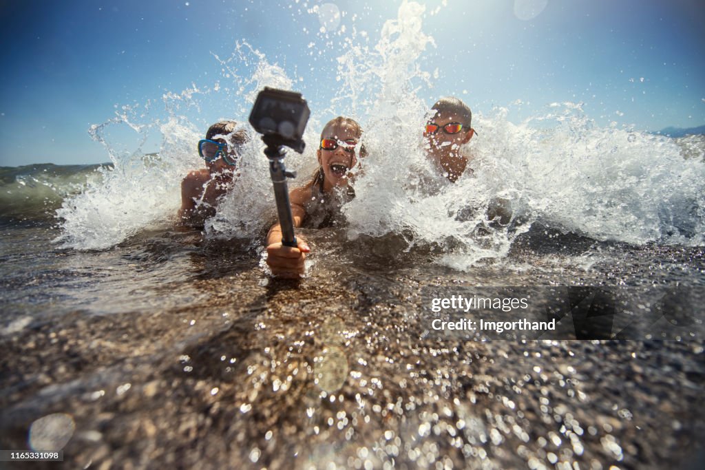 Kinderen spelen in zee golven en filmen zichzelf met behulp van waterdichte actie camera.