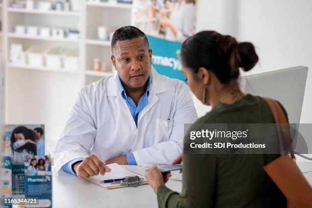 pharmacy customer talks with pharmacist about flu vaccine - pharmacy vaccination stock pictures, royalty-free photos & images