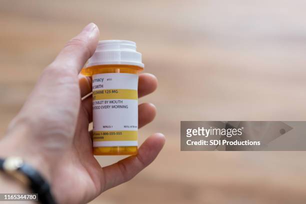 man holds a prescription medication container - prescription medicine stock pictures, royalty-free photos & images